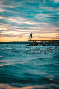 man on pier viewing sunrise over ocean